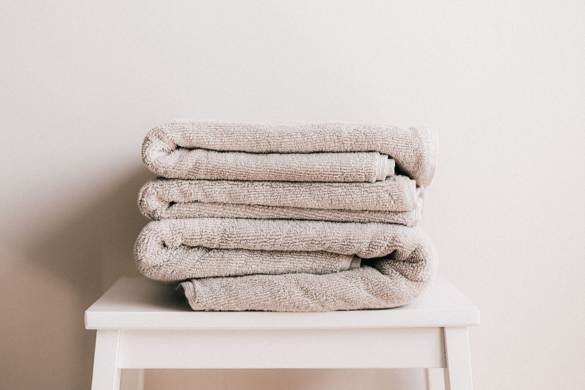 Folded beige towels on a white stool