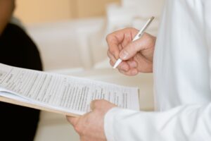 A hand writing clinical notes on a clipboard