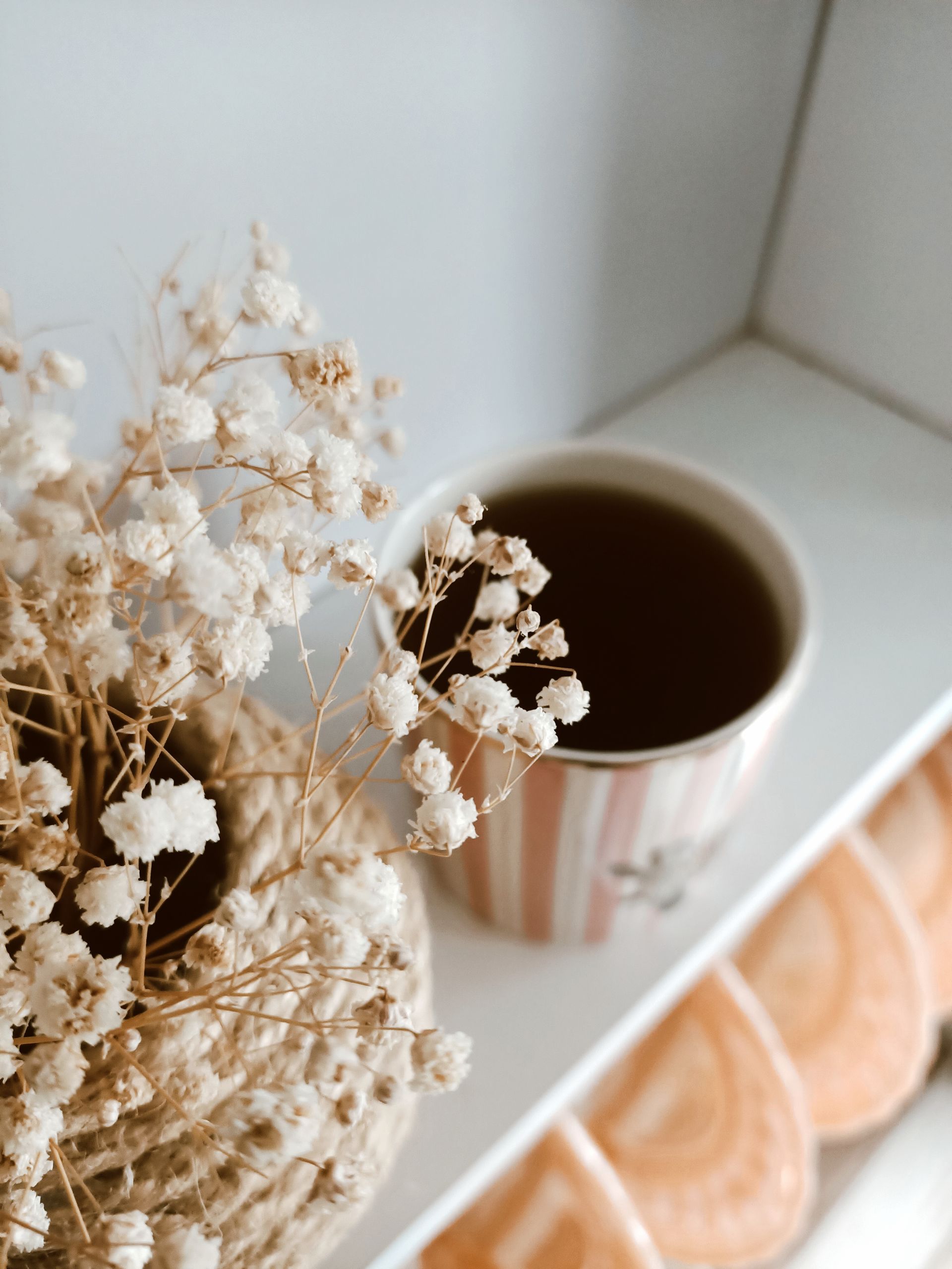A cup of tea beside dried flowers